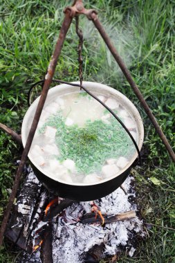 Tarladaki bir kazanda ateşte yemek pişirmek.