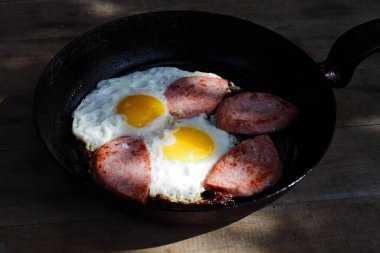 Tavada sosisli omlet, ahşap arka plan.