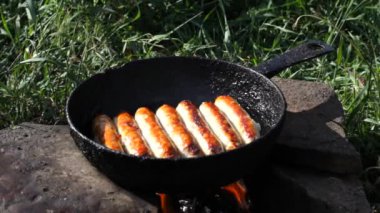 Sosisler tavada ateşte kızarıyor, dışarıda pişiriyor.