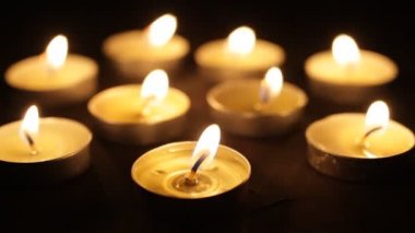 Mum yakıyorum. Karanlıkta birçok Noel mumu yanıyor. ön plana odaklan, mumlar odak dışı.