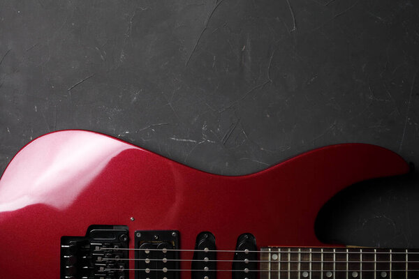 Red electric guitar on a dark concrete background, place for your text. View from above.