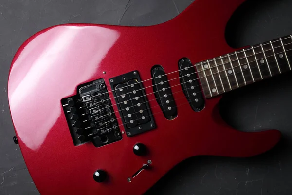 Red electric guitar on a dark concrete background, close-up, selective focus. view from above.