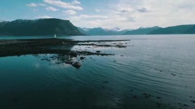 Yosun la kaplı taşlı bir plaj, havadan görüntüleri, Godoy adasında dağların arka planda deniz feneri Hogsteinen görünümü, Daha og Romsdal, Norveç 2019