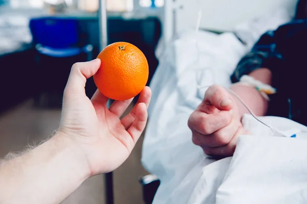 Médicos de la mano sostiene la naranja contra el gotero —  Fotos de Stock