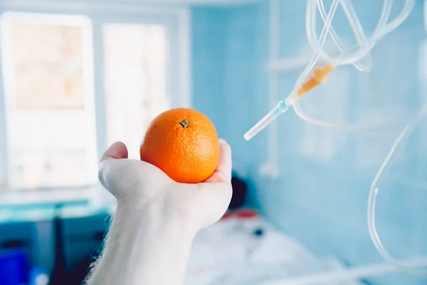 Médicos de la mano sostiene la naranja contra el gotero —  Fotos de Stock