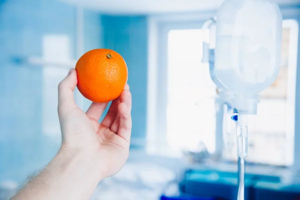 doctors hand holds the orange against the dropper