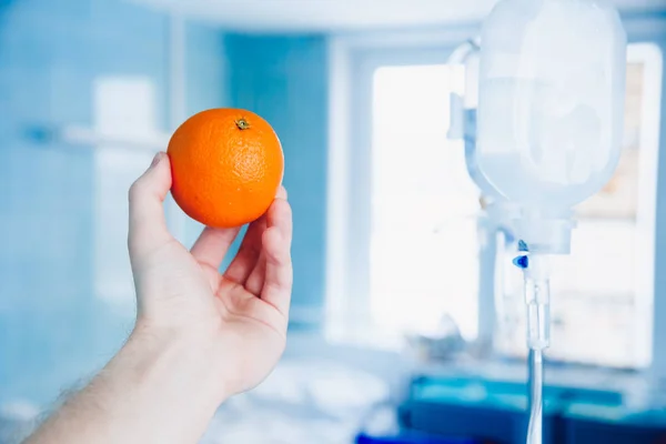 Médicos de la mano sostiene la naranja contra el gotero —  Fotos de Stock