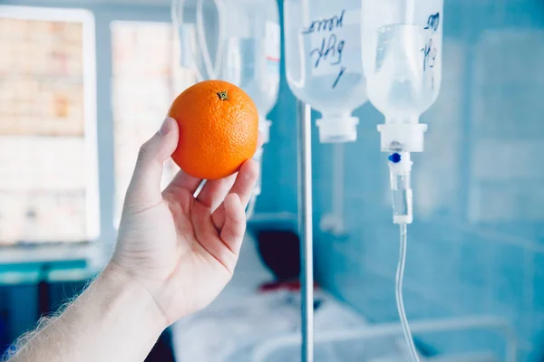 Médicos de la mano sostiene la naranja contra el gotero —  Fotos de Stock
