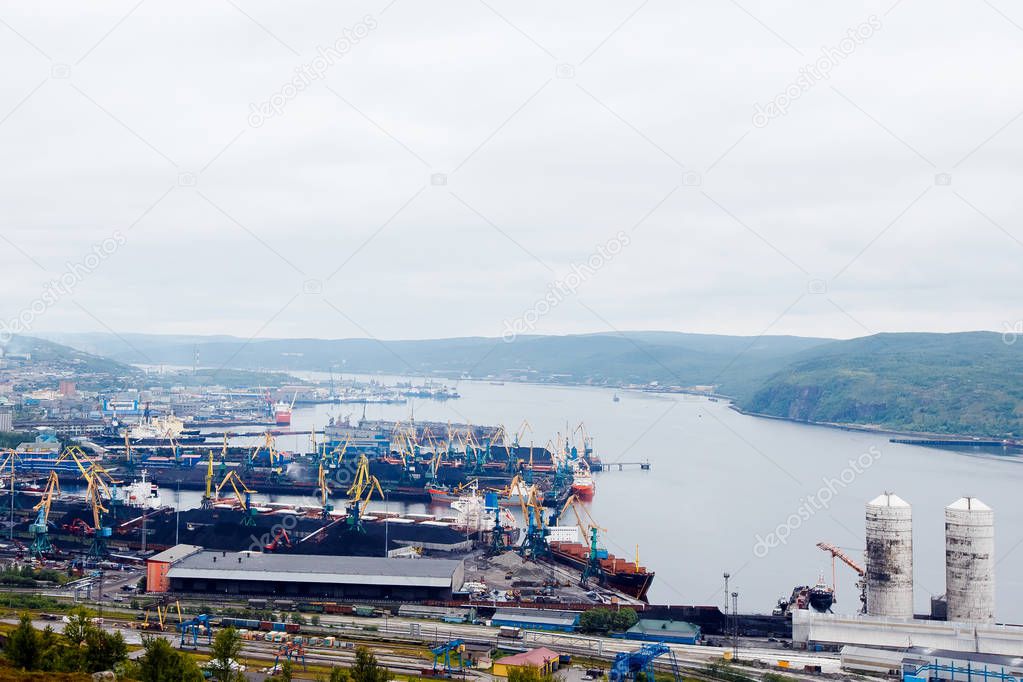 Embankment along with the river port, the crane unloads the coal from the box and loads it into the truck. Murmansk, Russia.Concept logistics, transportation, transport.