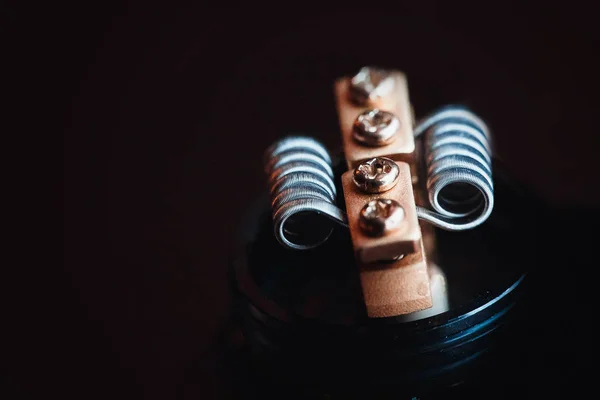 Coil spring close-up on a dark background. Vape, vaping. Firing a coil.