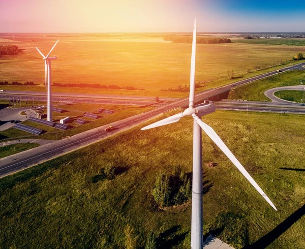 Wind generators on background of solar panels, ring road, truck and small forest areas bright summer Sunny day