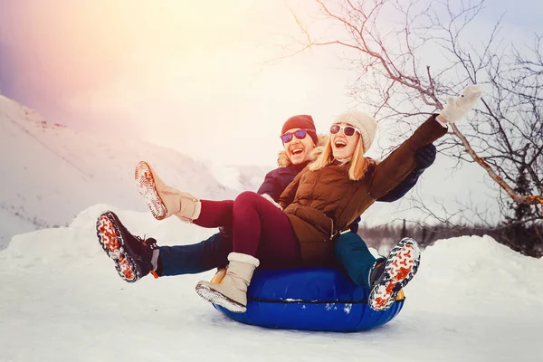 Happy people on tube outdoors in mountains in winter snow