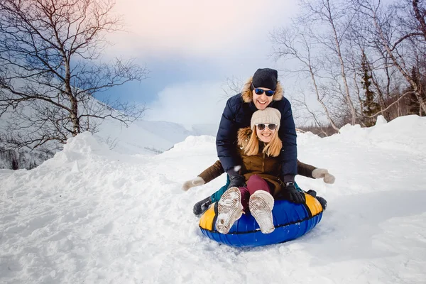 Happy people on tube outdoors in mountains in winter snow