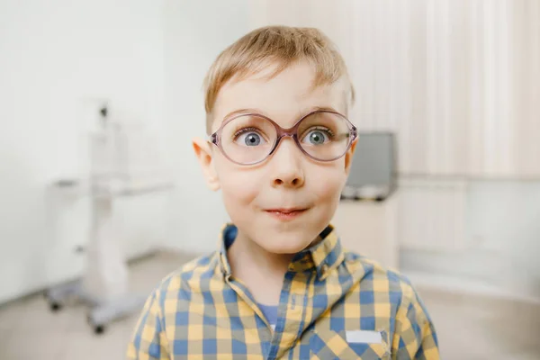 Sourire enfant garçon dans les lunettes vérifie la vision des yeux ophtalmologiste pédiatrique . — Photo