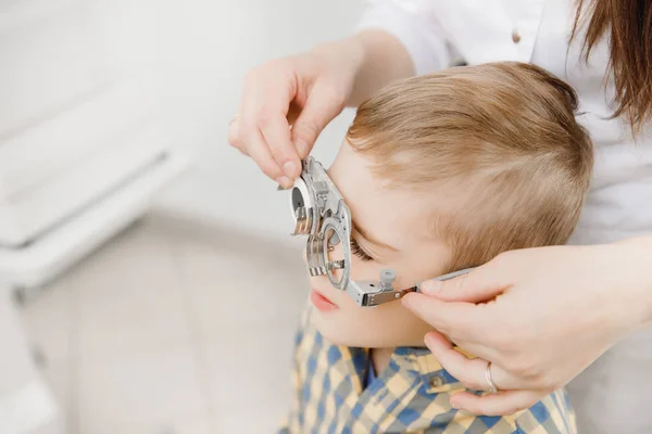 Παιδιατρικό οφθαλμολόγο ο γιατρός ελέγχει όραμα αγόρι παιδί. Επιλογής έννοιας της γυαλιά φακούς. — Φωτογραφία Αρχείου