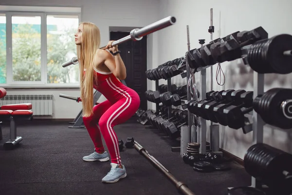 健身吧 在体育馆里做运动的女孩蹲着杠铃 健身房的概念健身 — 图库照片