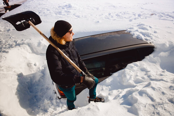 Man cleans snow and cleans car shovel from snow