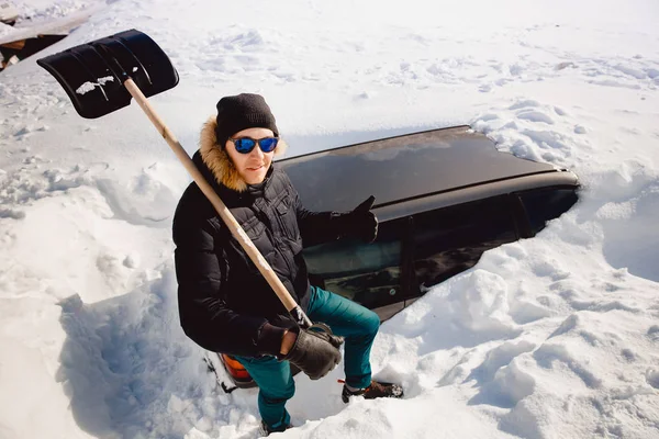 L'uomo pulisce la neve e pulisce la pala dell'auto dalla neve — Foto Stock