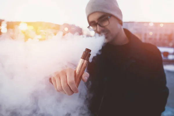 Człowiek w dymie posiada vape urządzenie elektroniczne — Zdjęcie stockowe