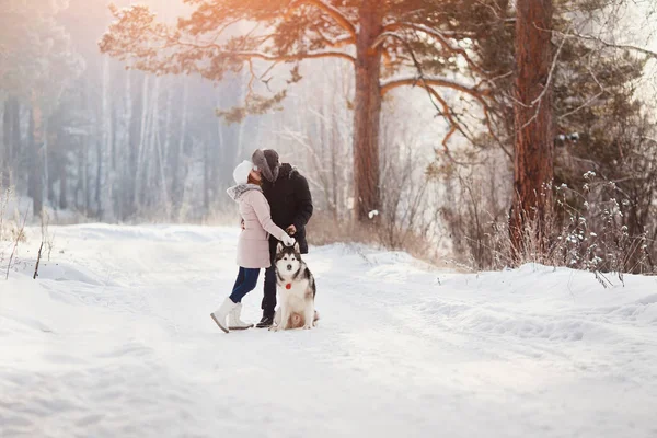 Coppia amante è a piedi nella neve con cane — Foto Stock