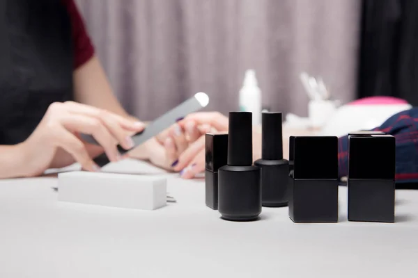 Close-up zwarte potten, flessen, containers van nagellak. Proces maken van manicure mooie vrouwelijke handen — Stockfoto