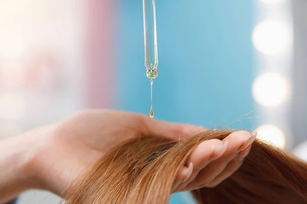 Yakından bir damla yağ alınır ve saç teli baş ampullerine uygulanır. Kuaför spa salonu.
