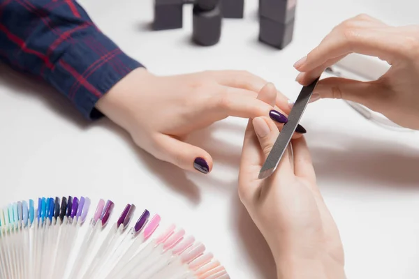 Manos de mujer manicura en el trabajo. Hermosas uñas brillantes violeta —  Fotos de Stock
