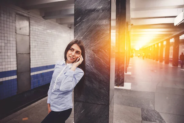 Young girl tourist talking on the phone in the subway and smiling — Stock Photo, Image