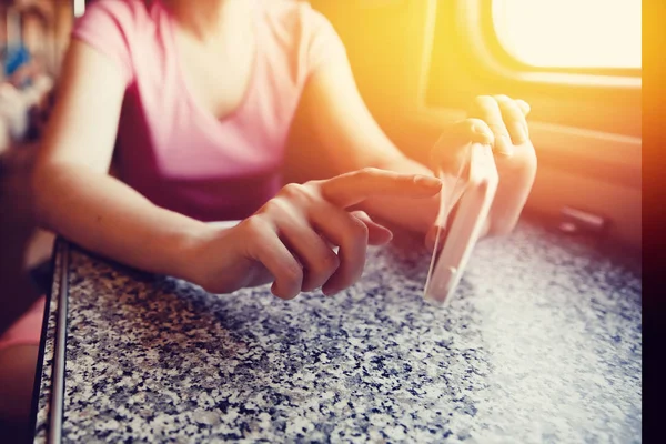Fille dans ses mains tient un téléphone portable et se met le doigt dans le voyage en train et en train dans la voiture . — Photo