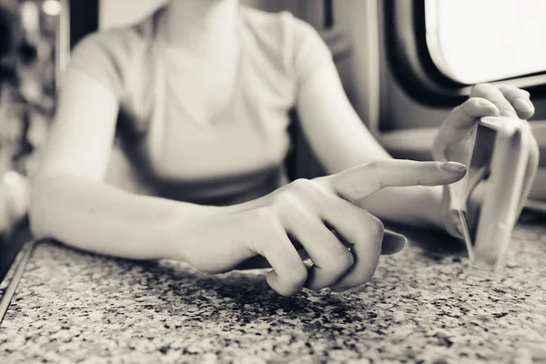 Дівчина в руках тримає мобільний телефон і штовхає палець у подорож на поїзді і поїзді в машині . — стокове фото