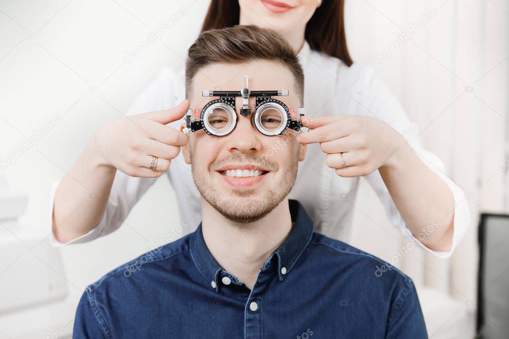 Man sits and smiles in an iron frame for selection of glasses lenses eyes reception ophthalmologist.