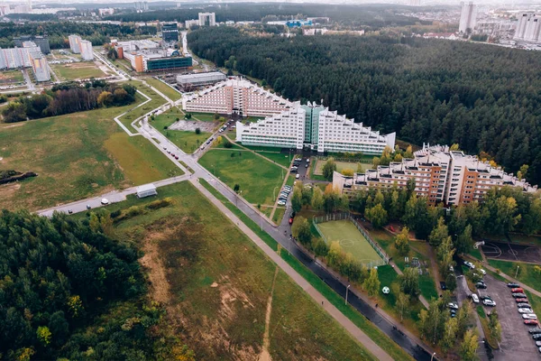 Městská krajina. Skladovací prostory. Parkování na rozdíl od sytě zelený Les, zažloutlé listy, trávy. Snížení sky. — Stock fotografie