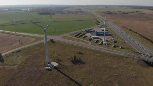 Painéis solares e moinhos de vento combinados de geração de energia estão na estrada, fornecem posto de gasolina e estufa. Vista superior — Vídeo de Stock