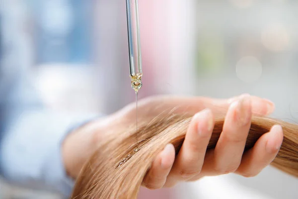 Майстер перукар застосовує олію для догляду за волоссям і відновлення росту кутикули жінки . — стокове фото