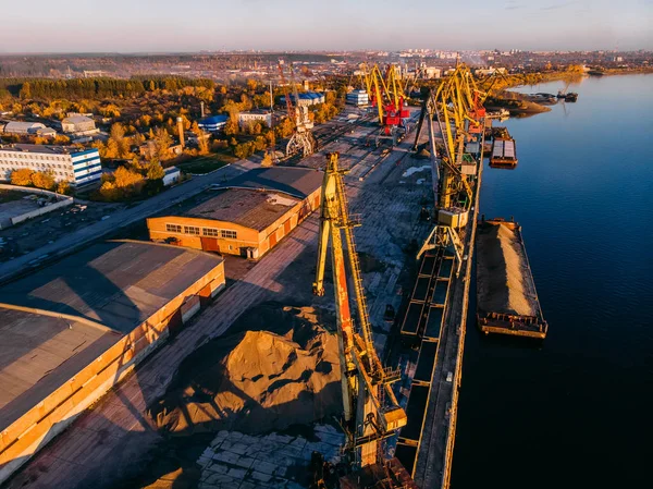 İskele nehir vinçleri mavna teslimatında gemileri yüklüyor, gün batımında. — Stok fotoğraf