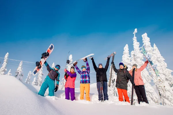 Grupo de gente alegre con esquís y tablas de snowboard juegan —  Fotos de Stock