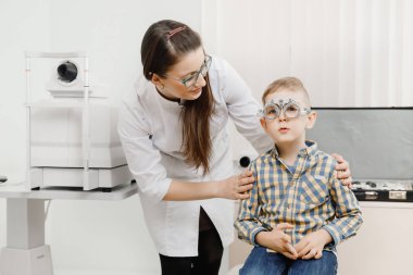 Pediatrik Doktor göz doktoruna çocuk çocuk vizyonu denetler. Gözlük lens kavramı seçimi.