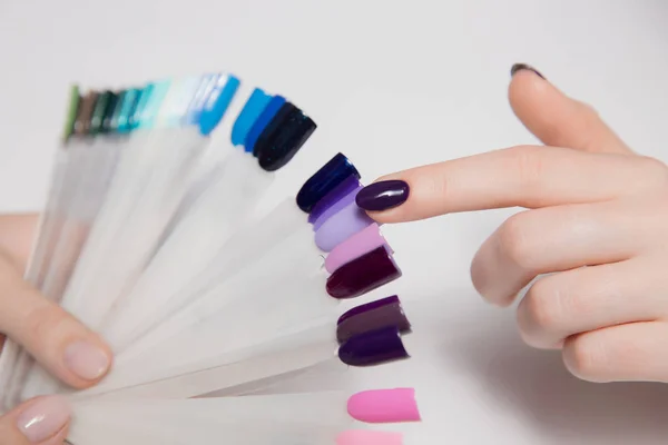 Mujeres manos de cerca. Chica con hermoso dedo manicura selecciona nuevo barniz de la paleta de colores —  Fotos de Stock
