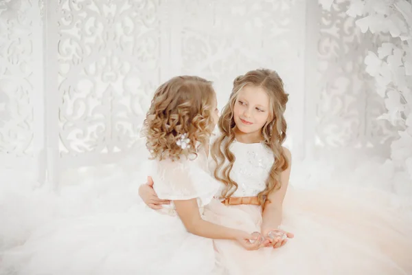 Duas irmãs menina bonita em vestido branco no fundo segurando cristais — Fotografia de Stock