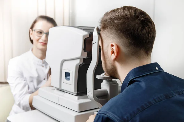 Mujer médico oftalmólogo clínica comprueba la visión ocular del hombre en la lámpara de la máquina . —  Fotos de Stock