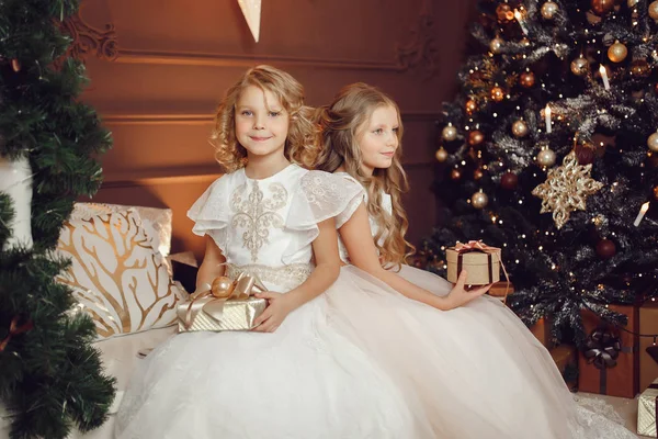 快乐的孩子女孩姐妹交换新年圣诞礼物背景的树灯 — 图库照片