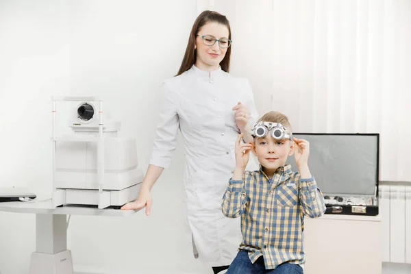 Médico oftalmologista pediátrico verifica a visão do menino. Seleção de conceito de lentes de óculos . — Fotografia de Stock