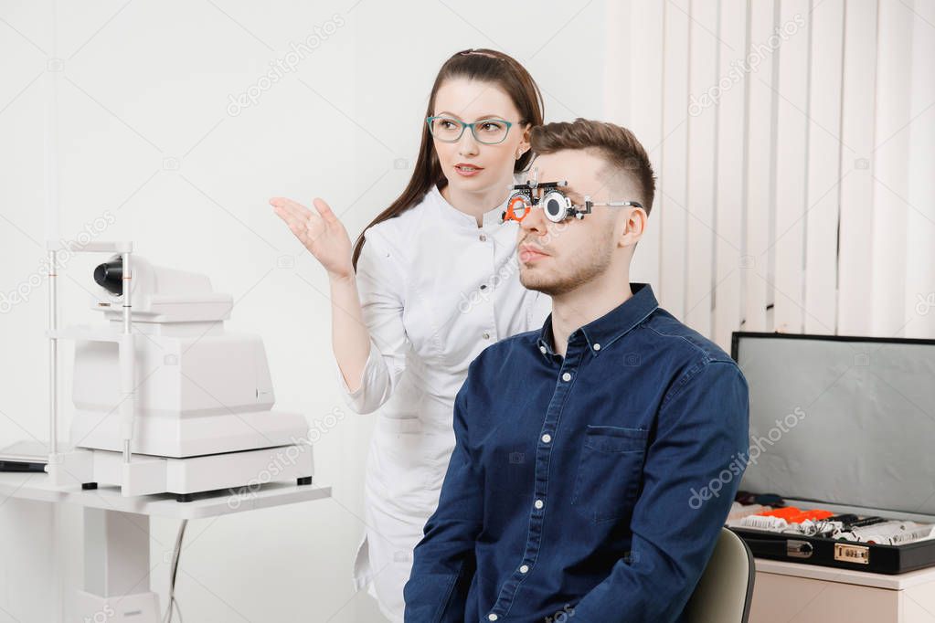 Ophthalmologist woman doctor checks diagnose eyesight myopia, hyperopia young man.
