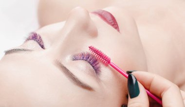 Kirpik uzatma yordamı. Uzun renkli tüyleri ile güzel kadın kirpik güzellik spa salonunda.