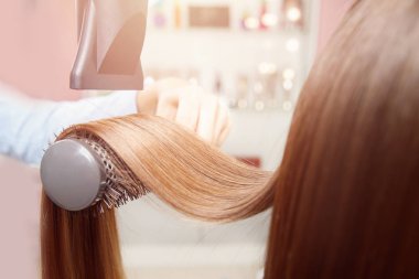 Kurutma ve şekillendirme parlak ipliklerini kurutma makinesi: koyu kahverengi saç yakın çekim. Kadınlar için güzellik salonu Master