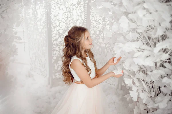 Weihnachten und Neujahr, Mädchen im weißen Kleid berührt künstlichen Baum. — Stockfoto