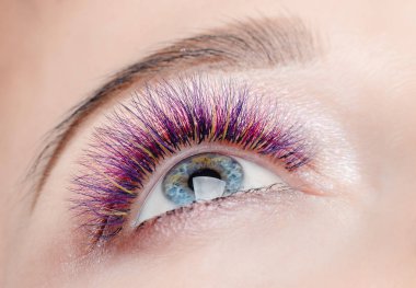 Kirpik uzatma yordamı. Uzun renkli tüyleri ile güzel kadın kirpik güzellik spa salonunda.