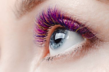 Kirpik uzatma yordamı. Uzun renkli tüyleri ile güzel kadın kirpik güzellik spa salonunda.