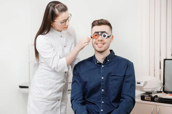 Οφθαλμίατρος γυναίκα ο γιατρός ελέγχει τη διάγνωση όρασης μυωπία, υπερμετρωπία νεαρός άνδρας. — Φωτογραφία Αρχείου