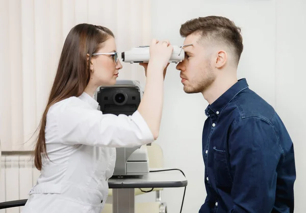 Médica feminina oftalmologista clínica verifica visão ocular do homem na lâmpada da máquina . — Fotografia de Stock
